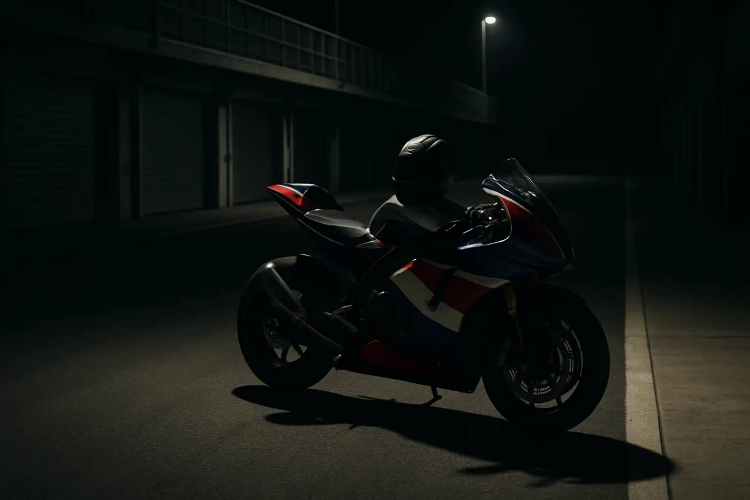 A MotoGP racing motorcycle on track with an empty pit lane in the background